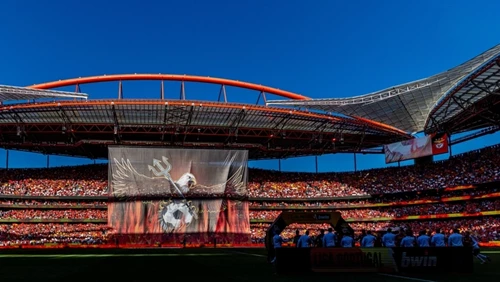 Blick auf das ausverkaufte Estádio da Luz bei strahlendem Himmel mit einem gigantischen Banner des Vereinsadlers, der einen Dreizack hält, im Zentrum des Spielfelds.